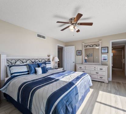 Drift off peacefully in your coastal bedroom featuring crisp blue linens, warm wood floors, and gentle ceiling fan breezes.