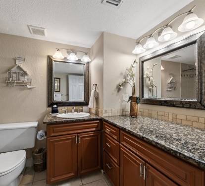 Pamper yourself in this elegantly appointed bathroom featuring granite countertops, rich wood cabinetry, and a spacious walk-in shower.