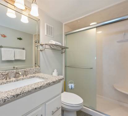 Your private bathroom features granite countertops, bright vanity lighting, and a spacious glass-enclosed shower for refreshing starts to each day.