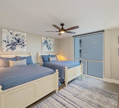 Drift off to sleep in this serene twin bedroom, where coastal blue linens and gentle ceiling fan create your perfect retreat.