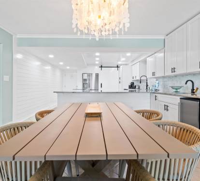 Gather around this stunning dining table where memorable meals unfold beneath elegant chandelier light in your beautiful coastal kitchen.