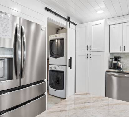 Your pristine white kitchen features stainless steel appliances and convenient laundry tucked behind sleek barn doors.