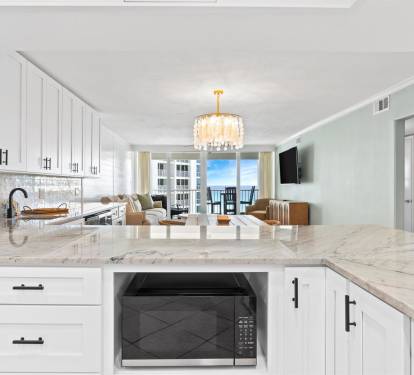 Your gourmet kitchen features gleaming marble countertops and elegant white cabinetry, perfect for preparing meals while enjoying ocean views.