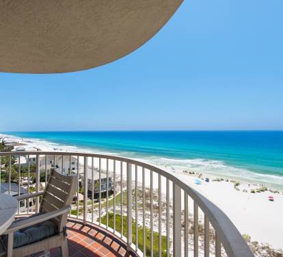 A curved balcony overlooks a pristine white sand beach and turquoise Gulf waters, offering an elevated coastal perspective for arrival at this beachfront property.