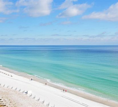 Pristine white sand beach with crystal-clear turquoise waters stretches endlessly along the Gulf Coast.