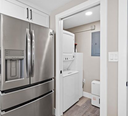 Your modern kitchen flows seamlessly into a convenient laundry space, featuring stainless steel appliances and pristine white cabinetry for effortless meal prep and housekeeping.