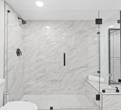 Step into your luxurious marble bathroom featuring a stunning glass-enclosed shower with rainfall head and elegant built-in seating bench.