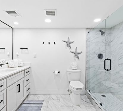 Step into your luxurious marble sanctuary featuring a spacious walk-in shower and elegant coastal touches that make every morning feel like a spa retreat.