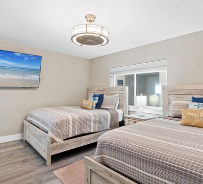 Rest peacefully in your Queen bed haven with coastal charm, modern ceiling fan, and beach views on the wall-mounted TV.