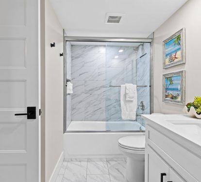 Step into your spa-like bathroom featuring elegant marble shower, pristine finishes, and coastal artwork that sets a peaceful tone for your morning routine.