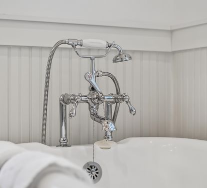 Sink into vintage luxury with this elegant clawfoot tub featuring polished chrome fixtures and classic wainscoting for your perfect soak.
