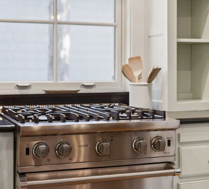 Cook your favorite meals on this professional-grade gas range with sleek stainless steel finish and modern white cabinetry.