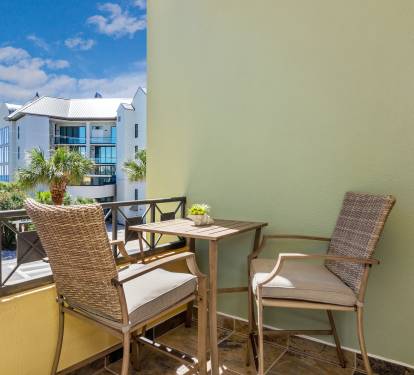 Cozy private balcony with bistro seating and palm-lined views—perfect for morning coffee or evening drinks on 30A.