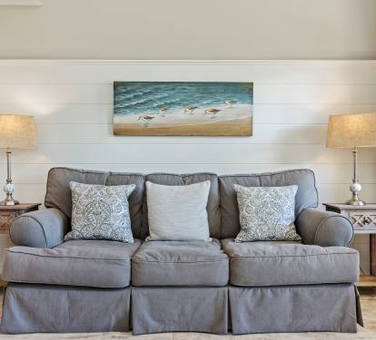 Cozy coastal-style queen sleeper sofa framed by beachy artwork and warm lighting—perfect for relaxing after a day at the beach or accommodating extra guests during your 30A getaway.