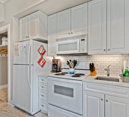Fully equipped kitchen with crisp white cabinetry, modern appliances, and a sleek subway tile backsplash—ideal for whipping up meals during your 30A stay.
