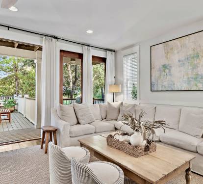 Unwind in the plush, inviting living room that opens directly to a beautiful deck overlooking a peaceful green space — the perfect spot for morning coffee or sunset cocktails.