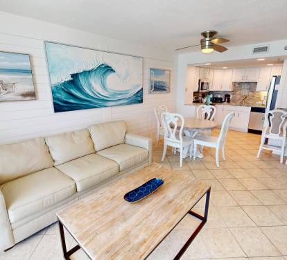 Picture yourself unwinding in this bright, coastal retreat. Soft white walls, beach-inspired artwork, and a spacious open layout invite you to relax. Your kitchen gleams just beyond, ready for morning coffee or sunset snacks.