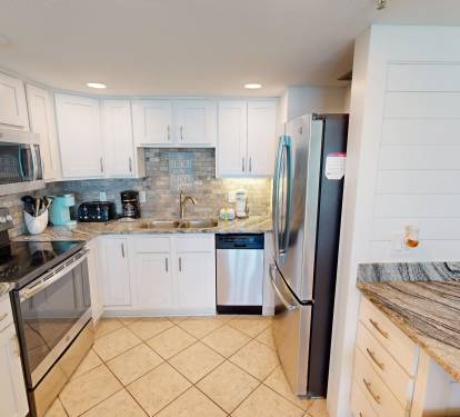 Picture yourself preparing meals in this bright, fully-equipped kitchen with modern appliances and granite countertops. Stainless steel refrigerator, oven, microwave, and dishwasher make cooking effortless while you enjoy your beachside getaway.