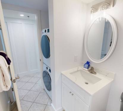 Your bathroom is fresh and functional, with a bright vanity, oval mirror, fluffy towels, and convenient in-unit washer and dryer to keep your stay comfortable and easy.