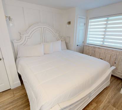 Your serene bedroom features crisp white linens and elegant coastal-style furnishings, inviting restful nights after exploring the area.