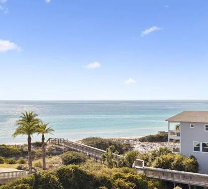 Coastal property featuring direct beach access via boardwalk, tropical landscaping, and stunning ocean views in a serene beachfront community.