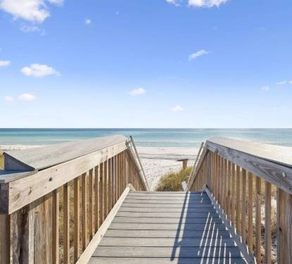 Private boardwalk leads directly to pristine white sand beach and crystal-clear turquoise waters under sunny skies, offering easy access to your coastal escape.