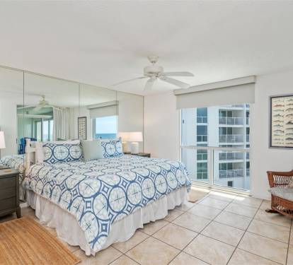 Wake up refreshed in your airy bedroom with coastal blue linens and a cozy wicker chair perfect for morning coffee.