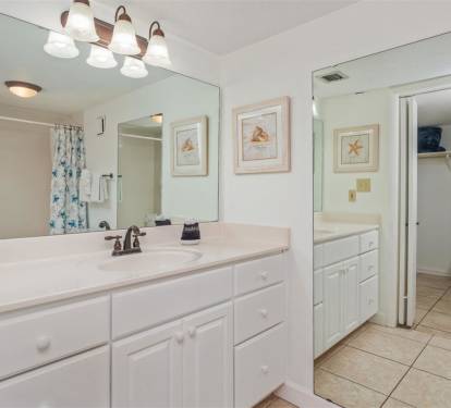 Refresh in your spacious bathroom featuring dual vanities, ample storage, and coastal-themed artwork that brings beach vibes to your morning routine.