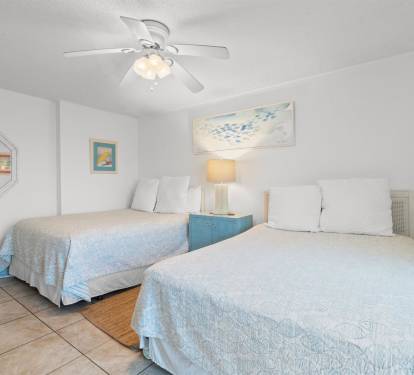 Rest easy in your peaceful bedroom with twin beds, gentle ceiling fan, and calming coastal decor for ultimate relaxation.