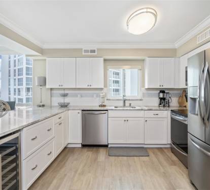 Your modern kitchen gleams with white cabinets and stainless steel appliances, while city views through bright windows inspire your culinary adventures.