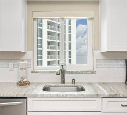 Start your morning routine in this bright, modern kitchen where granite counters and city views create the perfect coffee corner.