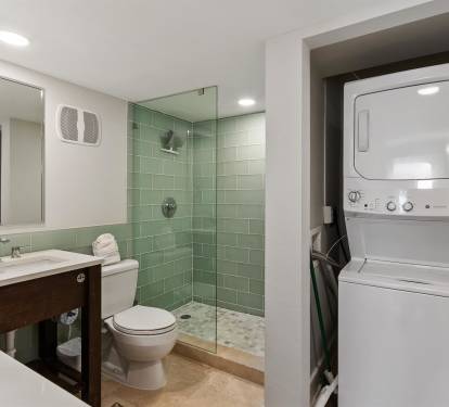 Your modern bathroom features spa-inspired green tiles and glass shower, plus convenient stacked washer-dryer for ultimate comfort.