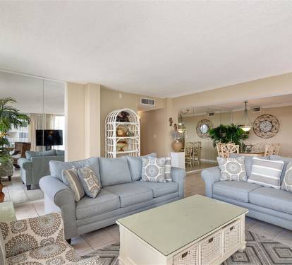 Unwind in your spacious living room with soft blue sofas, coastal décor, and gentle natural light streaming through.