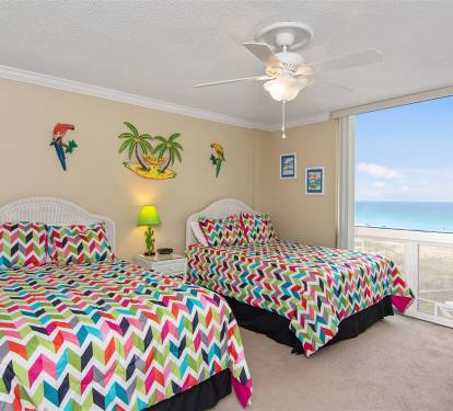 Wake up to stunning ocean views from your vibrant bedroom, where tropical decor and colorful chevron bedding create a cheerful coastal retreat.