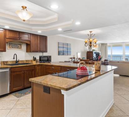 Your spacious kitchen features granite countertops, rich wood cabinetry, and an island perfect for meal prep while enjoying ocean views.