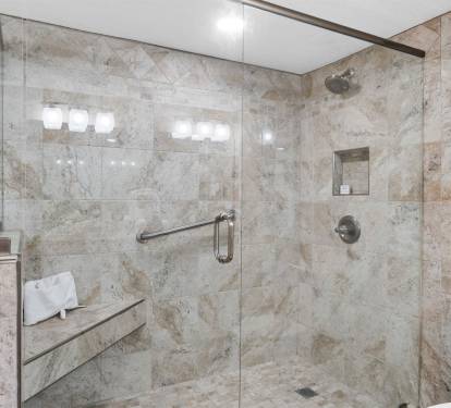 Step into your luxurious spa-like bathroom featuring elegant marble tiling and a spacious glass walk-in shower.