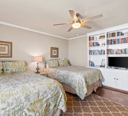 Unwind in your peaceful twin bedroom, featuring built-in shelving, entertainment center, and tropical bedding for ultimate comfort.