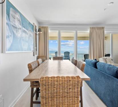 Gather around the natural wood dining table while gazing at stunning ocean views through floor-to-ceiling windows.