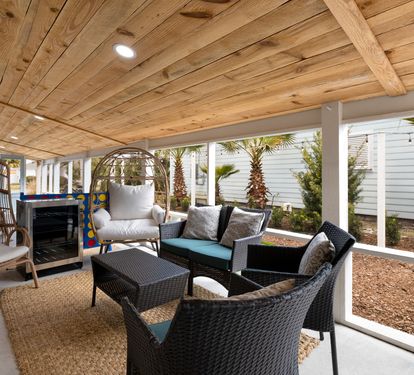 Settle into your private covered patio where rustic wood beams frame comfortable seating and cooling fans create the perfect outdoor retreat.