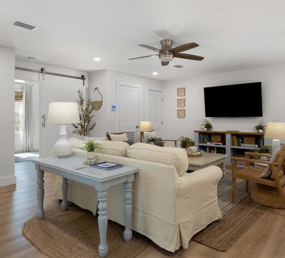 Unwind in your bright, modern living room with cozy seating, entertainment center, and coastal touches throughout.