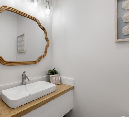 Fresh up in your stylish powder room with elegant gold mirror and coastal touches.