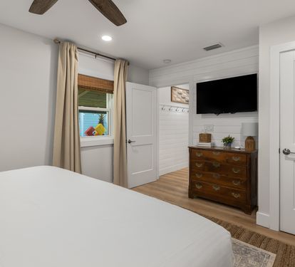 Drift off to sleep in your peaceful bedroom featuring rustic wood beams overhead, a mounted TV for evening relaxation, and warm touches throughout this inviting space.