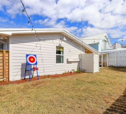 Modern white home features a private fenced backyard with lawn space and children's play equipment in a quiet residential neighborhood.