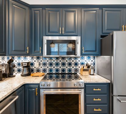 Your stunning kitchen features rich navy cabinets with gold accents and beautiful patterned tile backsplash, perfect for creating memorable meals.