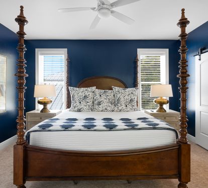 Unwind in your elegant bedroom featuring a stunning four-poster bed, rich navy walls, and coastal artwork that creates a sophisticated coastal retreat.