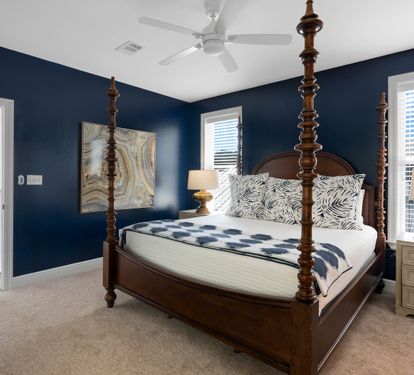 Sink into this elegant four-poster bed surrounded by rich navy walls and coastal charm, creating your perfect retreat.
