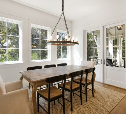 Gather around this elegant dining table where warm conversations flow beneath the rustic chandelier, with garden views framing every meal.