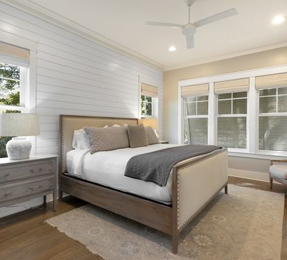 Unwind in this elegant bedroom with crisp white linens and natural light streaming through large windows.