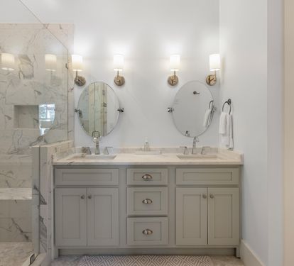 Step into your luxurious marble bathroom featuring dual sinks, elegant brass sconces, and a spacious glass-enclosed shower for ultimate relaxation.