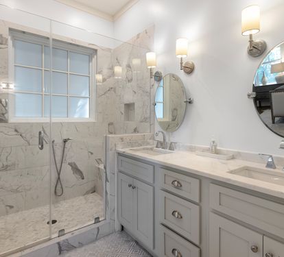 Step into your luxurious marble bathroom with a spacious walk-in shower and elegant dual vanities, perfect for your morning routine.